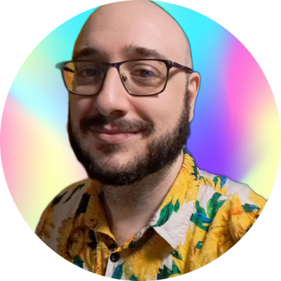 Treyson, a Caucasian nonbinary person in their late 30s. Their head is shaved, and they have a mustache and beard. They are wearing black glasses, a yellow eyebrow piercing, and a sunflower-print button-down shirt.