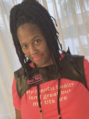 pretty brownskinned girl with high top loc ponytail in hot pink tee with leather harness vest and bright pink lipstick